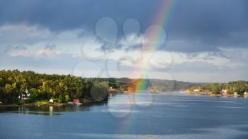 panorama of green coast of Baltic Sea with villages and rainbow over water in sunny autumn day, Sweden