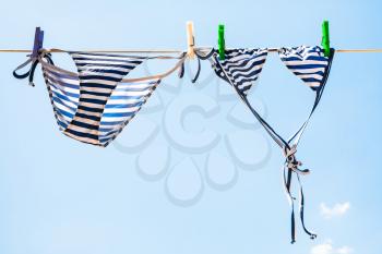 Striped female swim suit is dried on clothesline outdoors
