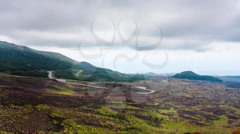 travel to Italy - low cloudy sky over road in lava fields on Mount Etna in Sicily in summer day