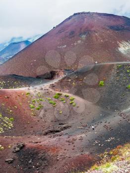 travel to Italy - tourists on path between big craters on Mount Etna in Sicily in summer day