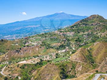 travel to Italy - view of green hills with villages and Etna volcano in Sicily