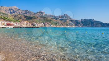 travel to Italy - view of Taormina city on mountain of Cape Taormina and Giardini Naxos village on the coast of Ionian sea in Sicily in summer day