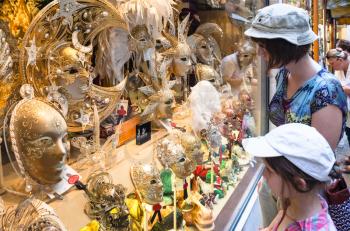 VENICE, ITALY - JUNE 23, 2011: tourist view on expensive carnival masks in shop window of Venice city. The first written mention of masks on holidays in Venice refers to 1268.