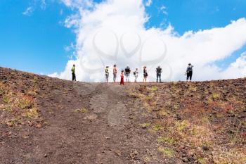 ETNA, ITALY - JULY 1, 2011 - tourists on the edge of old crater of Etna volcano. Mount Etna is active volcano on the east coast of Sicily, the tallest active volcano in Europe