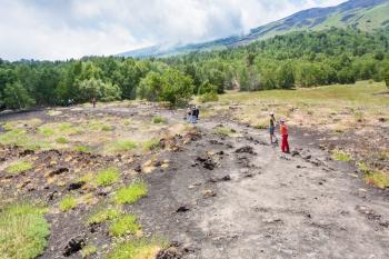 ETNA, ITALY - JULY 1, 2011 - tourists walk on path on slope of Etna mount. Mount Etna is active volcano on the east coast of Sicily, the tallest active volcano in Europe