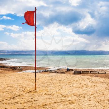 Travel to Middle East country Kingdom of Jordan - red flag on beach of Dead Sea in winter season