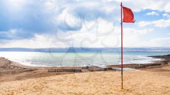 Travel to Middle East country Kingdom of Jordan - red flag on beach in cold day on Dead Sea in winter season