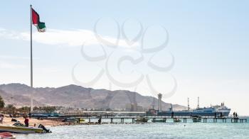 AQABA, JORDAN - FEBRUARY 23, 2012: view of urban beach and Sea port in Aqaba city. Jordan country has only one exit to Red sea and only one port in Gulf of Aqaba.