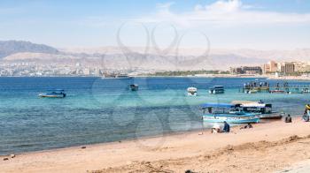 AQABA, JORDAN - FEBRUARY 23, 2012: Aqaba city beach and view of Eilat city in the background in winter day. Jordan country has only one exit to sea in Gulf of Aqaba, the length of the coast is 27 km