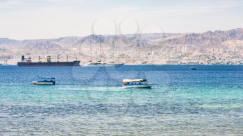 AQABA, JORDAN - FEBRUARY 23, 2012: boats in Gulf of Aqaba and view of Eilat city in the background in winter. Jordan country has only one exit to sea in Gulf of Aqaba, the length of the coast is 27 km