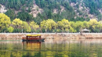 travel to China - view of ship in Yi river and green East Hill of Longmen grottoes area in spring season