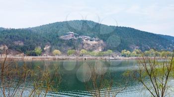 travel to China - panoramic view of green East Hill with temples of Chinese Buddhist monument Longmen Grottoes (Dragon's Gate Grottoes, Longmen Caves) on Yi river in spring season.