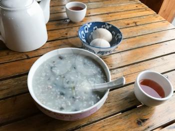 travel to China - served local chinese breakfast from eggs and congree rice porridge with century eggs (pidan) in rustic eatery in area Dazhai Longsheng Rice Terraces country in spring