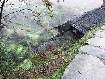 travel to China - view of wet hut and terraced fields from Tiantouzhai village in spring rain in area of Dazhai Longsheng Rice Terraces (Dragon's Backbone terrace, Longji Rice Terraces) country