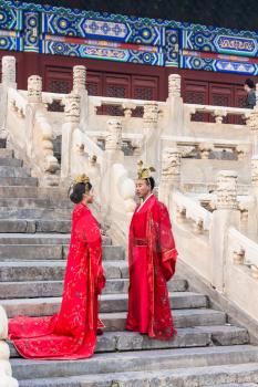 BEIJING, CHINA - MARCH 19, 2017: couple in traditional dresses on steps of Hall for Worship of Ancestors in Imperial Ancestral Temple (Taimiao) in Beijing Imperial city in spring.
