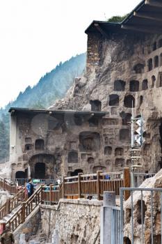 LUOYANG, CHINA - MARCH 20, 2017: people near caves in Chinese Buddhist monument Longmen Grottoes (Longmen Caves). The complex was inscribed upon the UNESCO World Heritage List in 2000
