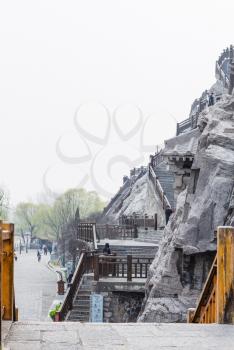LUOYANG, CHINA - MARCH 20, 2017: tourists and carved slope in Chinese Buddhist monument Longmen Grottoes (Longmen Caves). The complex was inscribed upon the UNESCO World Heritage List in 2000