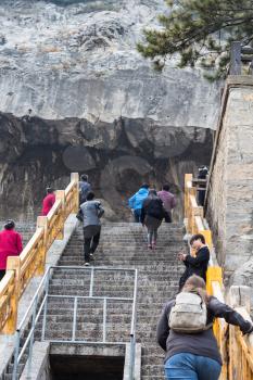 LUOYANG, CHINA - MARCH 20, 2017: tourists climb to cave in Chinese Buddhist monument Longmen Grottoes (Longmen Caves). The complex was inscribed upon the UNESCO World Heritage List in 2000