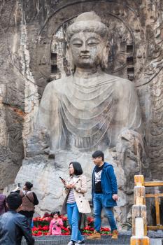 LUOYANG, CHINA - MARCH 20, 2017: tourists near The Big Vairocana statue in main Longmen Grottoes (Longmen Caves). The complex was inscribed upon the UNESCO World Heritage List in 2000