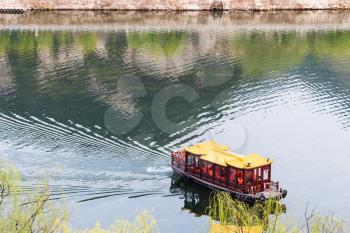 LUOYANG, CHINA - MARCH 20, 2017: ship on Yi river between West and East Hills of Chinese Buddhist monument Longmen Grottoes ( Longmen Caves) in spring season