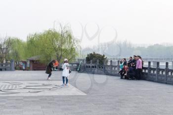 LUOYANG, CHINA - MARCH 20, 2017: tourists take photo in Chinese Buddhist monument Longmen Grottoes (Longmen Caves) in spring. The complex was inscribed upon the UNESCO World Heritage List in 2000