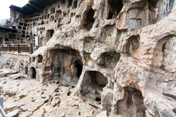 LUOYANG, CHINA - MARCH 20, 2017: caves and Grottoes in wall of West Hill of Chinese Buddhist monument Longmen Grottoes. The complex was inscribed upon the UNESCO World Heritage List in 2000