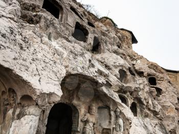 LUOYANG, CHINA - MARCH 20, 2017: carved slope of caves in West Hill of Chinese Buddhist monument Longmen Grottoes. The complex was inscribed upon the UNESCO World Heritage List in 2000
