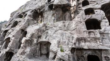 LUOYANG, CHINA - MARCH 20, 2017: carved figures and caves in slope of West Hill of Chinese Buddhist monument Longmen Grottoes. The complex was inscribed upon the UNESCO World Heritage List in 2000