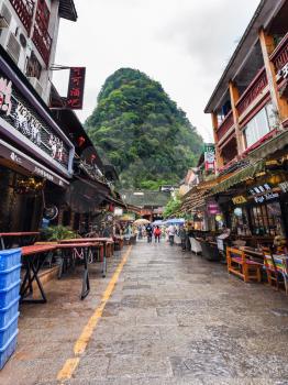 YANGSHUO, CHINA - MARCH 30, 2017: tourists on alley in Yangshuo town in spring. Town is resort destination for domestic and foreign tourists because of scenic karst peaks