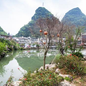 YANGSHUO, CHINA - MARCH 30, 2017: tree with lanterns on waterfront in Yangshuo town in spring. Town is resort destination for domestic and foreign tourists because of scenic karst peaks