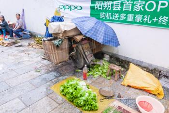 YANGSHUO, CHINA - MARCH 30, 2017: sellers and lettuce on street outdoor market in Yangshuo city in spring. Town is resort destination for domestic and foreign tourists because of scenic karst peaks