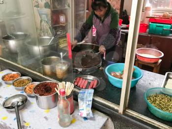 LONGSHENG, CHINA - MARCH 25, 2017: Chief cooks food in cheap urban eatery in Longsheng town. Longsheng is a small city in the south central Chinese province of Guangxi