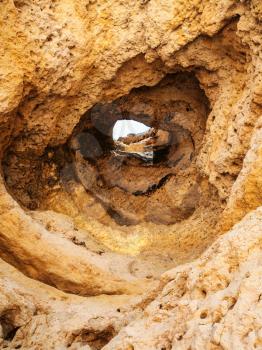 Travel to Algarve Portugal - hole in eroded sandstone mount on beach Praia Maria Luisa near Albufeira city in sunny day