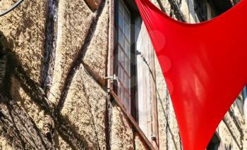 Travel to Occitanie, France - red flag and wall of old house in medieval town Cite de Carcassonne