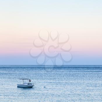 travel to Sicily, Italy - view of boat on blue water of Ionian sea near Giardini Naxos town in blue and pink summer twilight