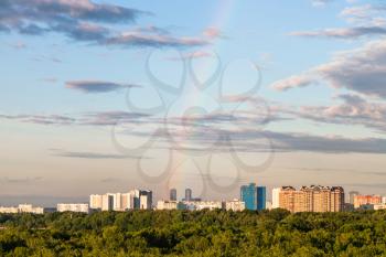 rainbow in blue evening sky over residential houses and Timiryazevsky park in Moscow city in summer