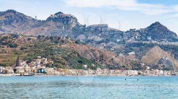 travel to Sicily, Italy - Ionian sea and view of Giardini Naxos town and Taormina city on cape in summer