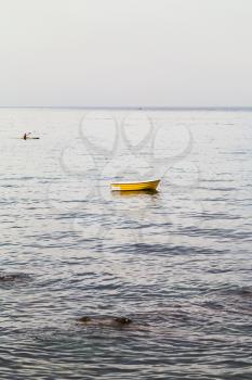 travel to Sicily, Italy - yellow boat in Ionian sea near waterfront in Giardini Naxos town in summer evening