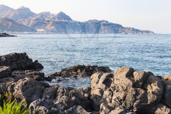 travel to Sicily, Italy - volcanic rocks coastline of Ionian sea in Giardini Naxos town in summer