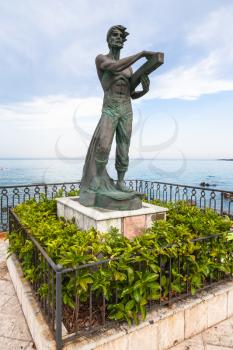 GIARDINI NAXOS, ITALY - JUNE 28, 2017: sculpture L' Uomo e il Mare (Man and the Sea) on waterfront in Giardini-Naxos town. Giardini Naxos is seaside resort on Ionian Sea coast since the 1970s