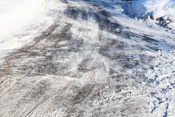 surface of snow-cleared slippery urban road in sunny winter day