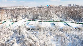 Moscow cityscape with snow-covered garages between urban Timiryazevsky park and apple orchard in Koptevo district in sunny winter day