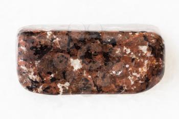 macro shooting of natural mineral rock specimen - polished spreusteined urtite stone on white marble background from Khibiny Mountains, Kola Peninsula, Russia