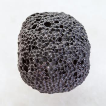 macro shooting of natural mineral rock specimen - black pumice bead on white marble background from Sicily