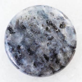 macro shooting of natural mineral rock specimen - cabochon from gray Labradorite gemstone on white marble background