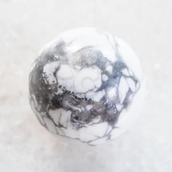 macro shooting of natural mineral rock specimen - bead from Howlite gemstone on white marble background