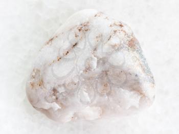 macro shooting of natural mineral rock specimen - tumbled marble stone on white marble background from Greece