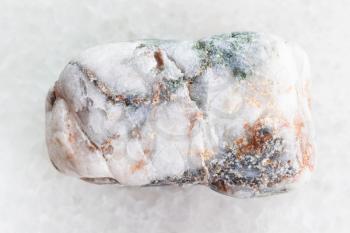 macro shooting of natural mineral rock specimen - tumbled marble pebble on white marble background from Greece
