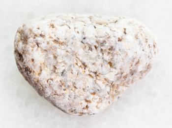 macro shooting of natural mineral rock specimen - pebble of white Granite stone on white marble background