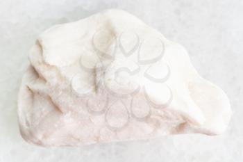 macro shooting of natural mineral rock specimen - pebble of white marble gemstone on white marble background from Greece
